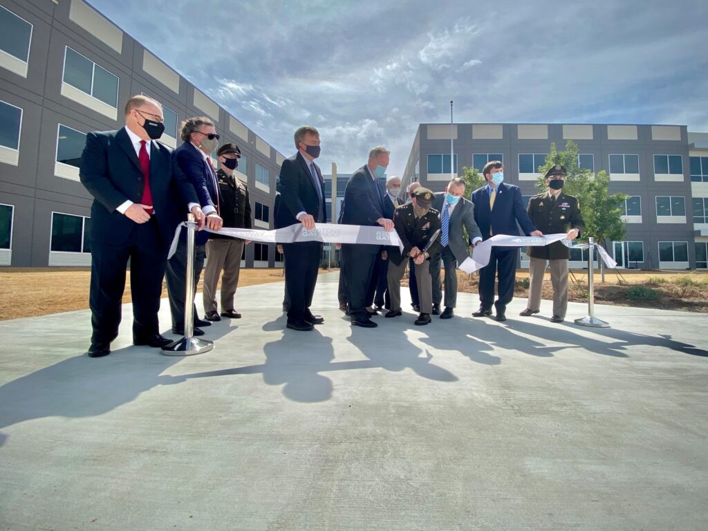 People standing in front of buildings cutting a ribbon