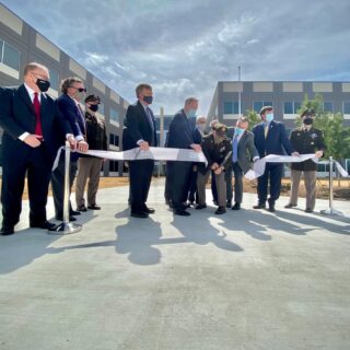 People standing in front of buildings cutting a ribbon